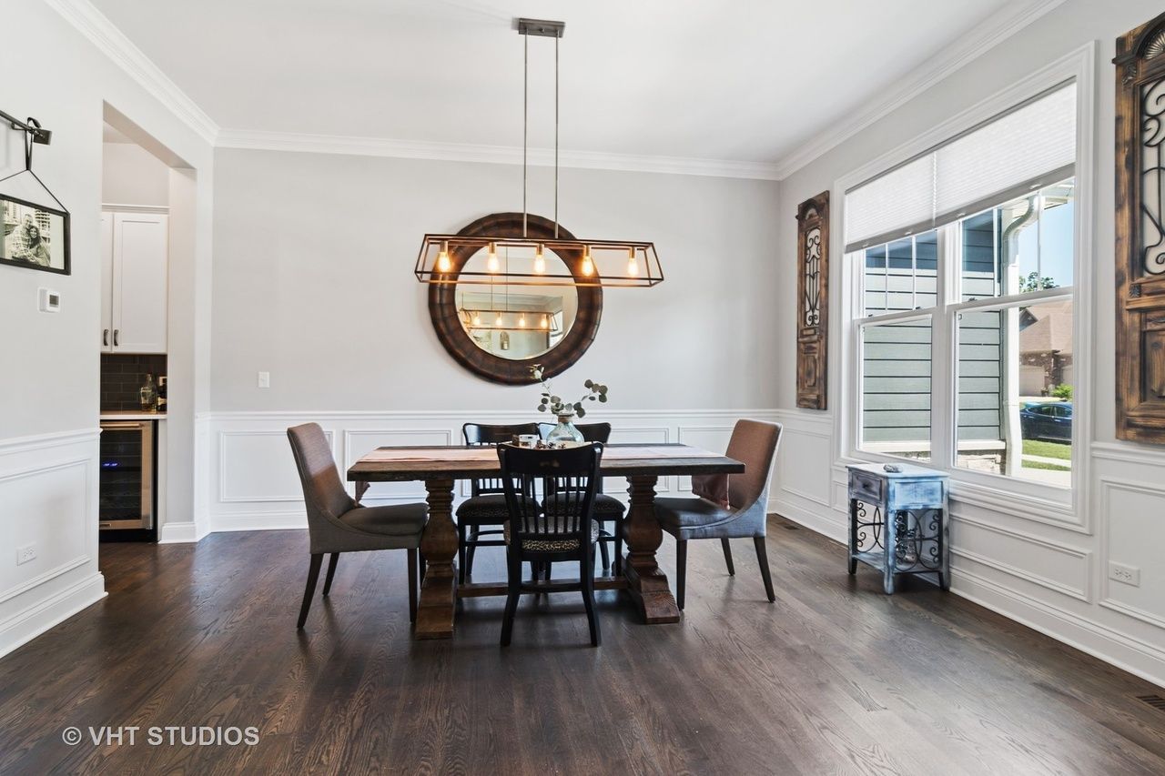 A dining room with a table and chairs and a mirror