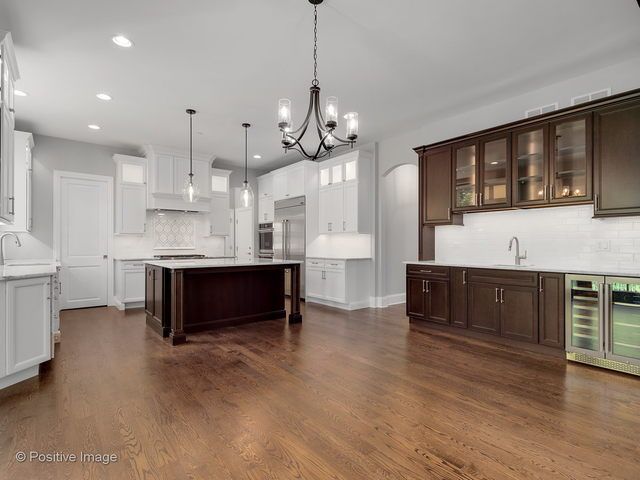 A large empty kitchen with wooden floors and white cabinets.