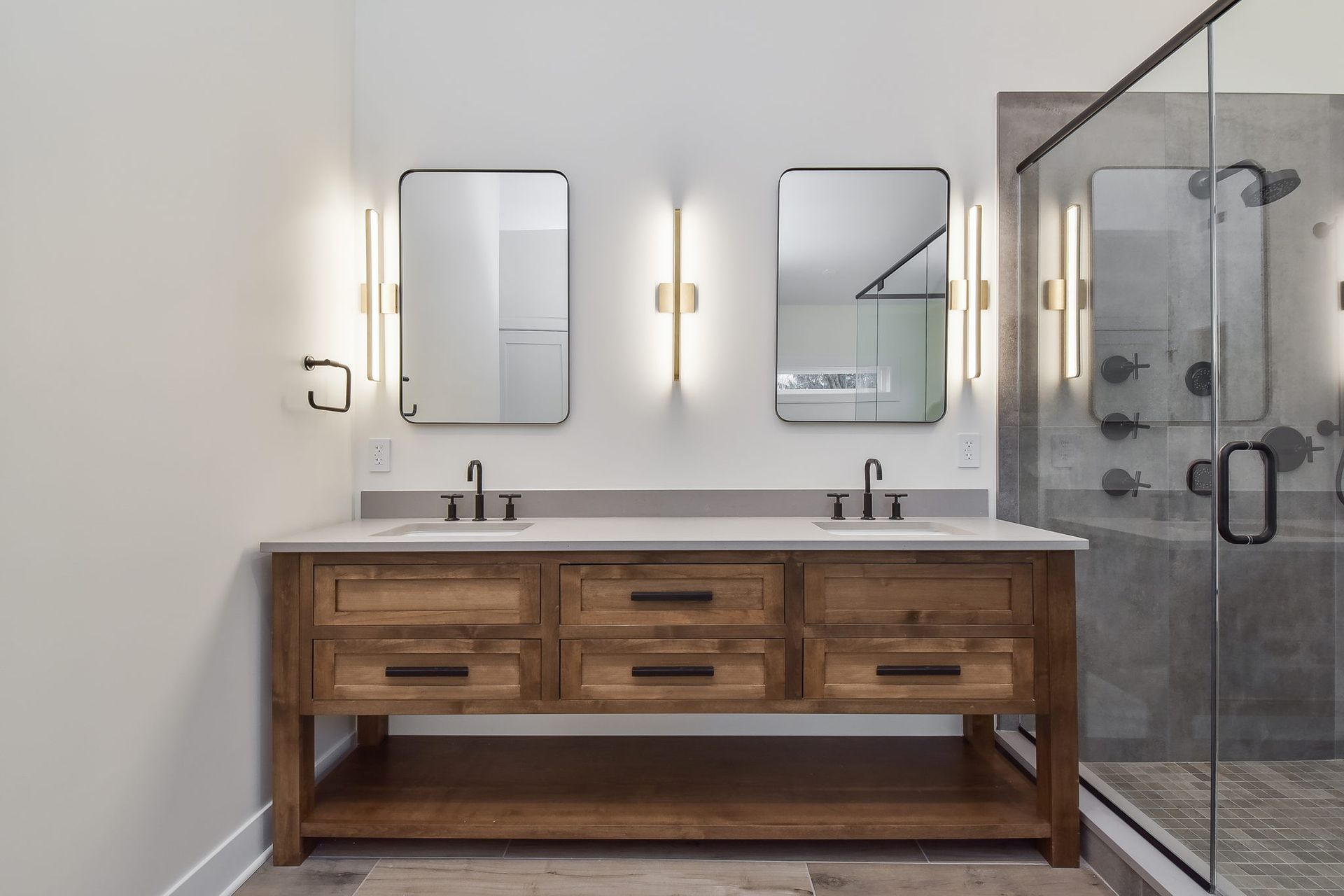 A bathroom with two sinks , two mirrors and a walk in shower.