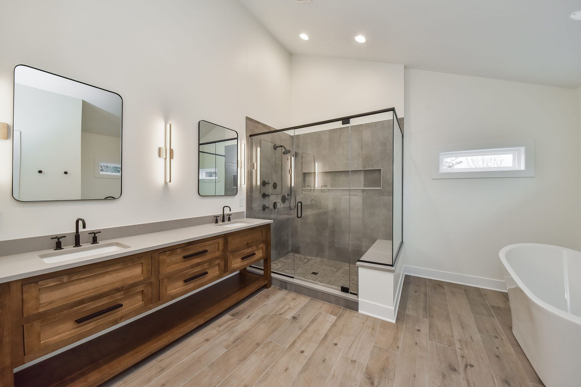 A bathroom with two sinks , a tub , and a walk in shower.