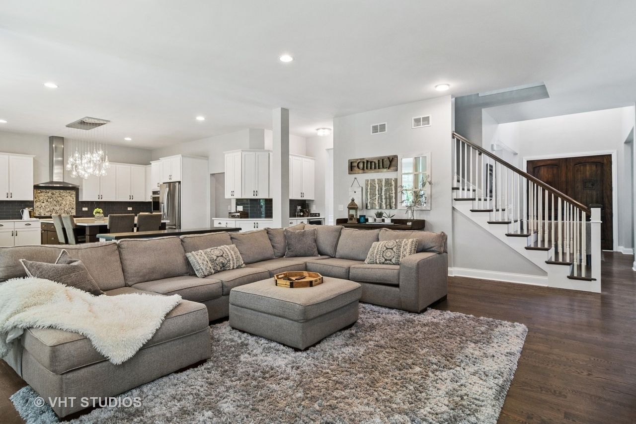 A living room with a large sectional couch , ottoman , and rug.