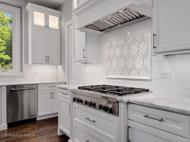 A kitchen with white cabinets and a stove top oven.