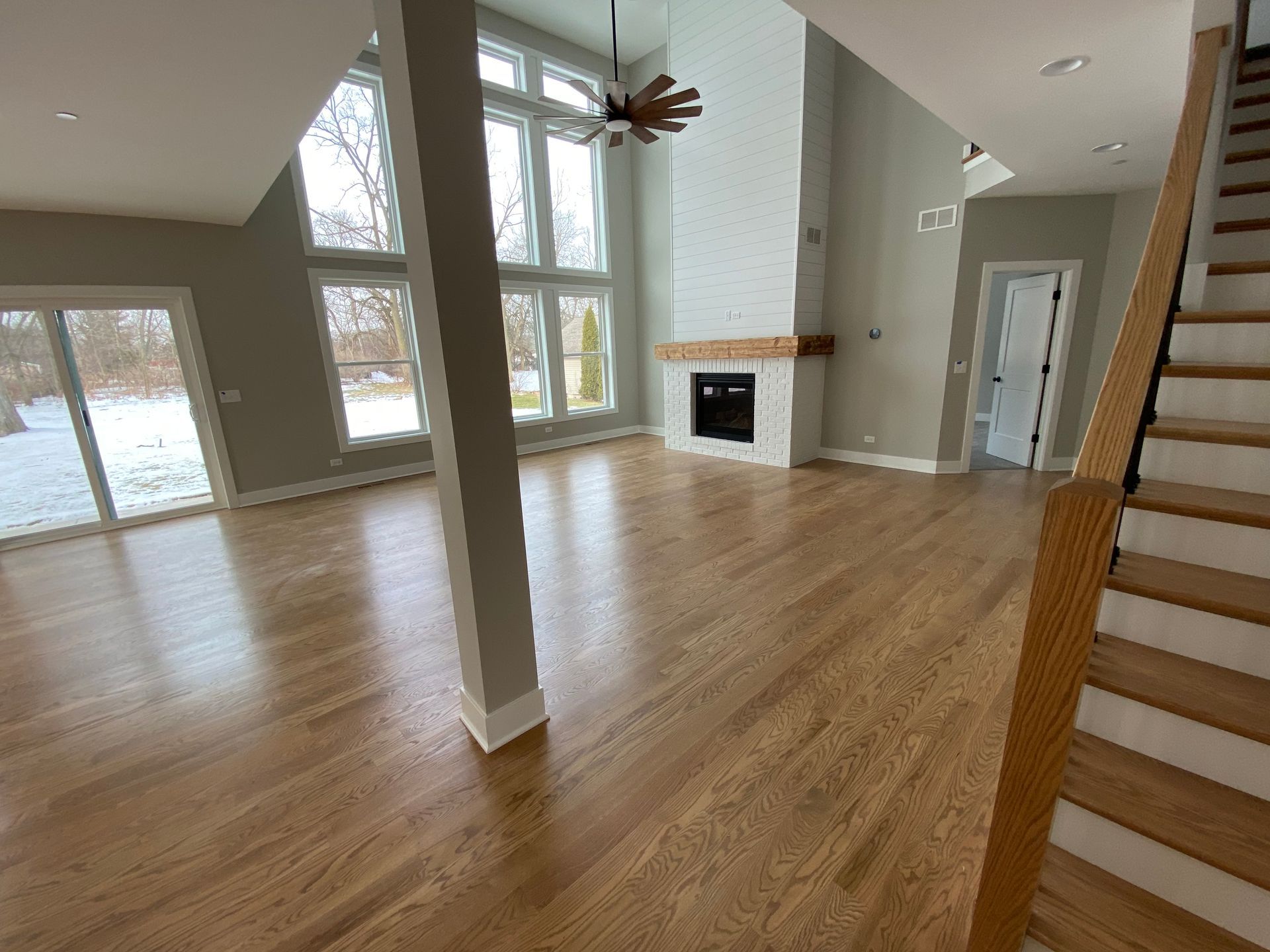 An empty living room with hardwood floors and stairs leading up to the second floor.