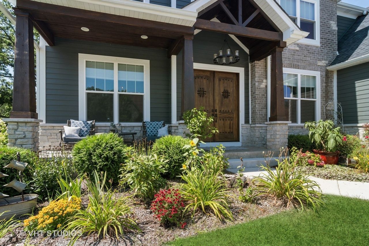 A house with a large porch and a lot of plants in front of it.