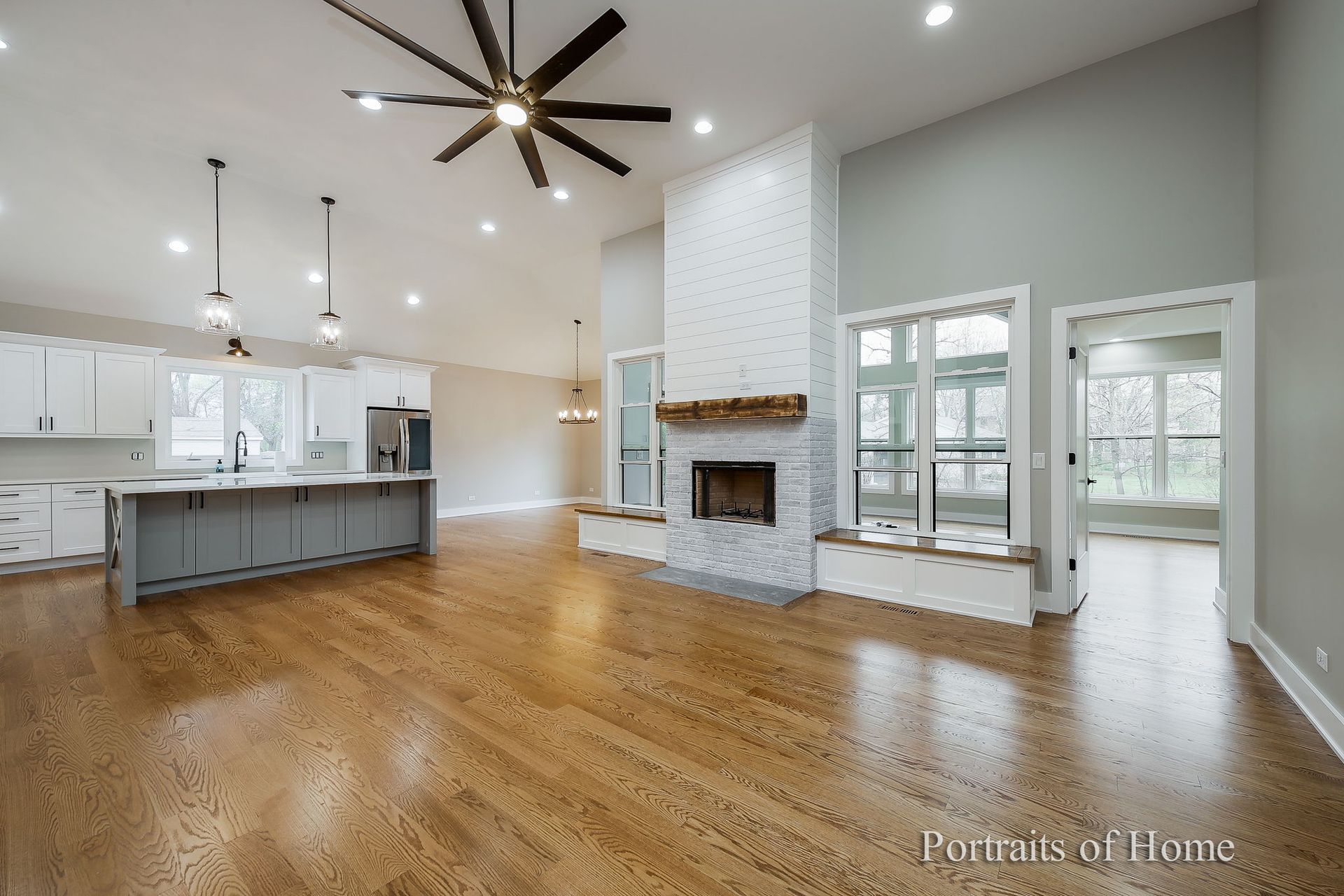 A living room with hardwood floors , a fireplace and a ceiling fan.