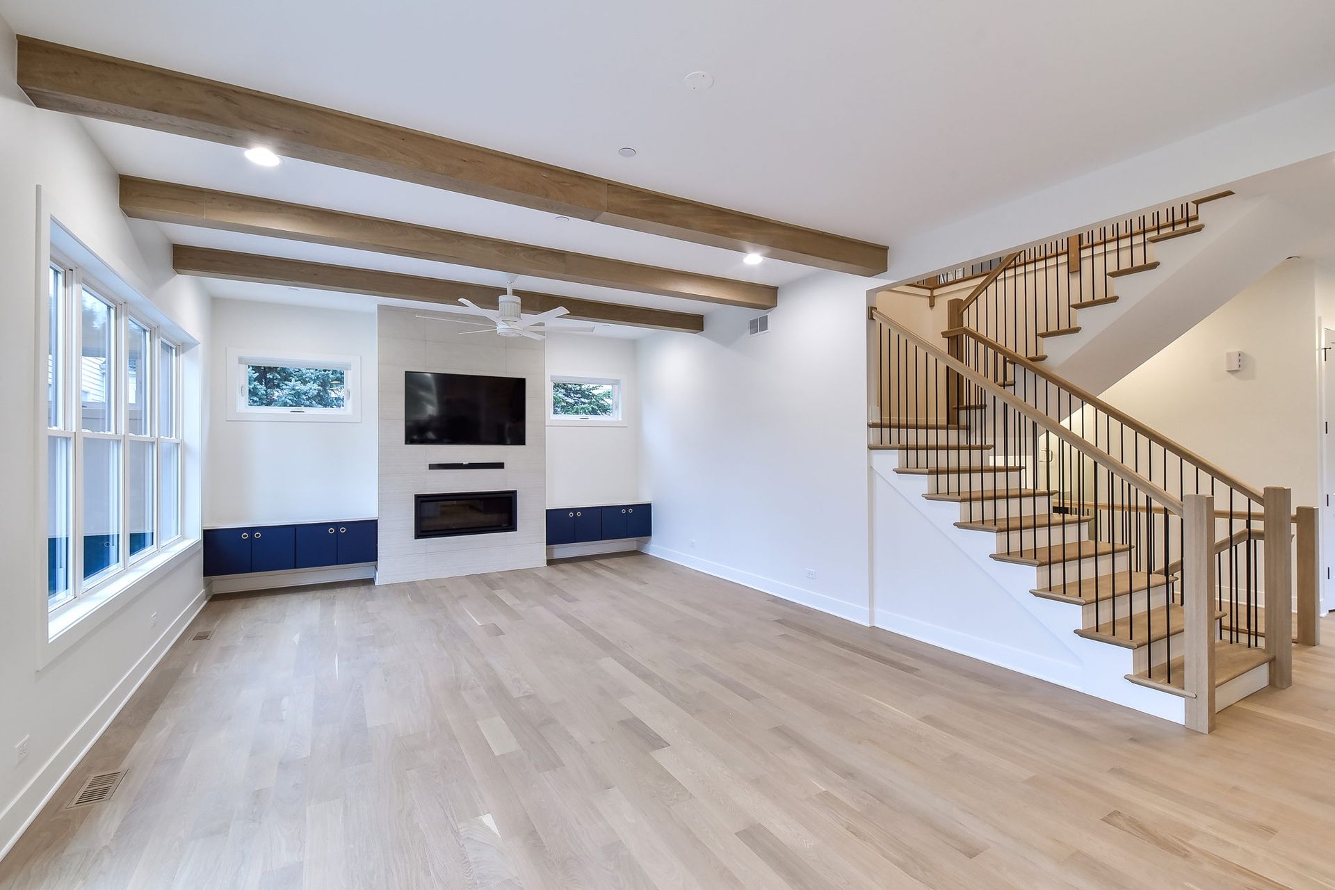An empty living room with a staircase and a flat screen tv.