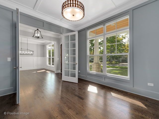 An empty room with hardwood floors and lots of windows.