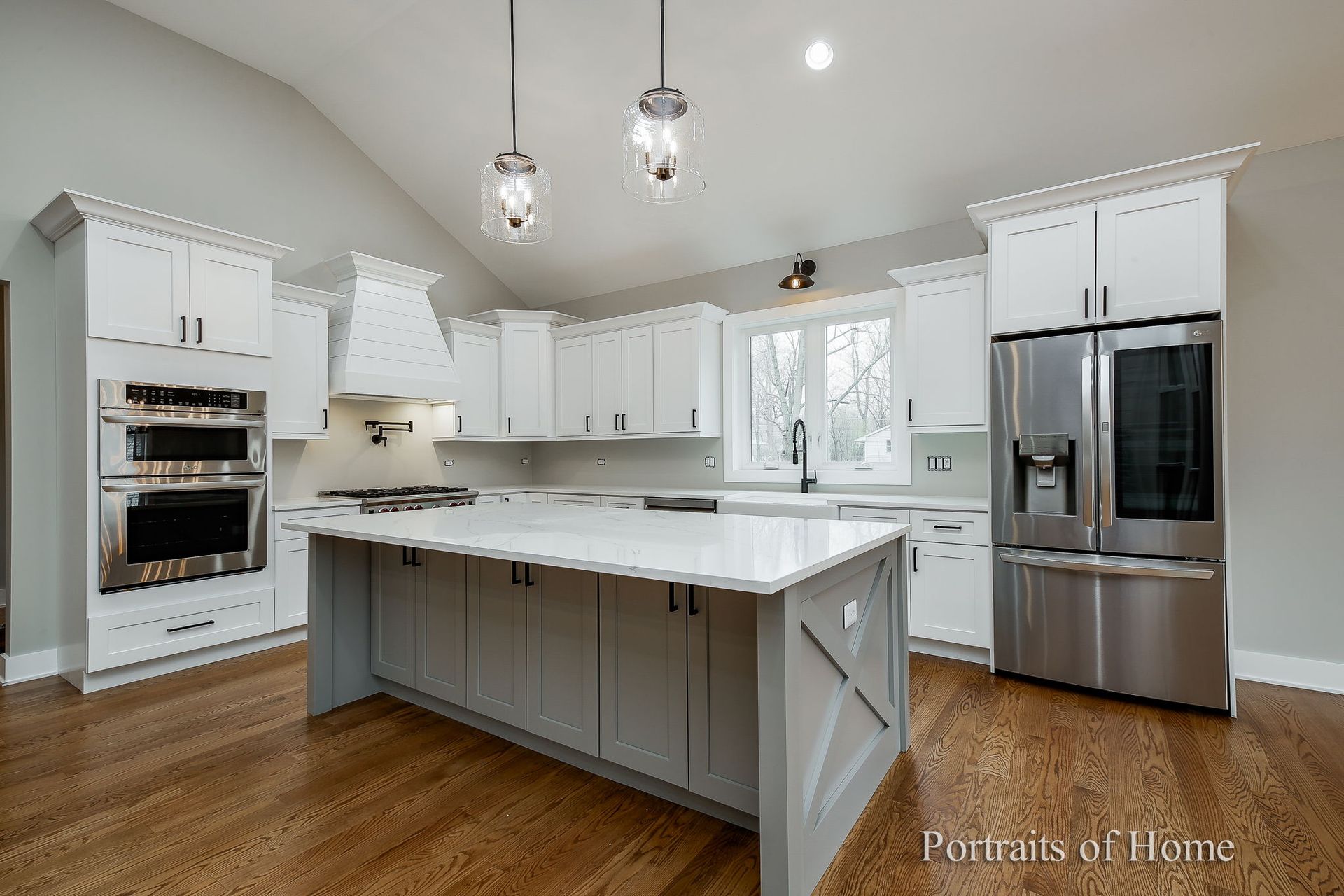 A kitchen with white cabinets , stainless steel appliances , and a large island.
