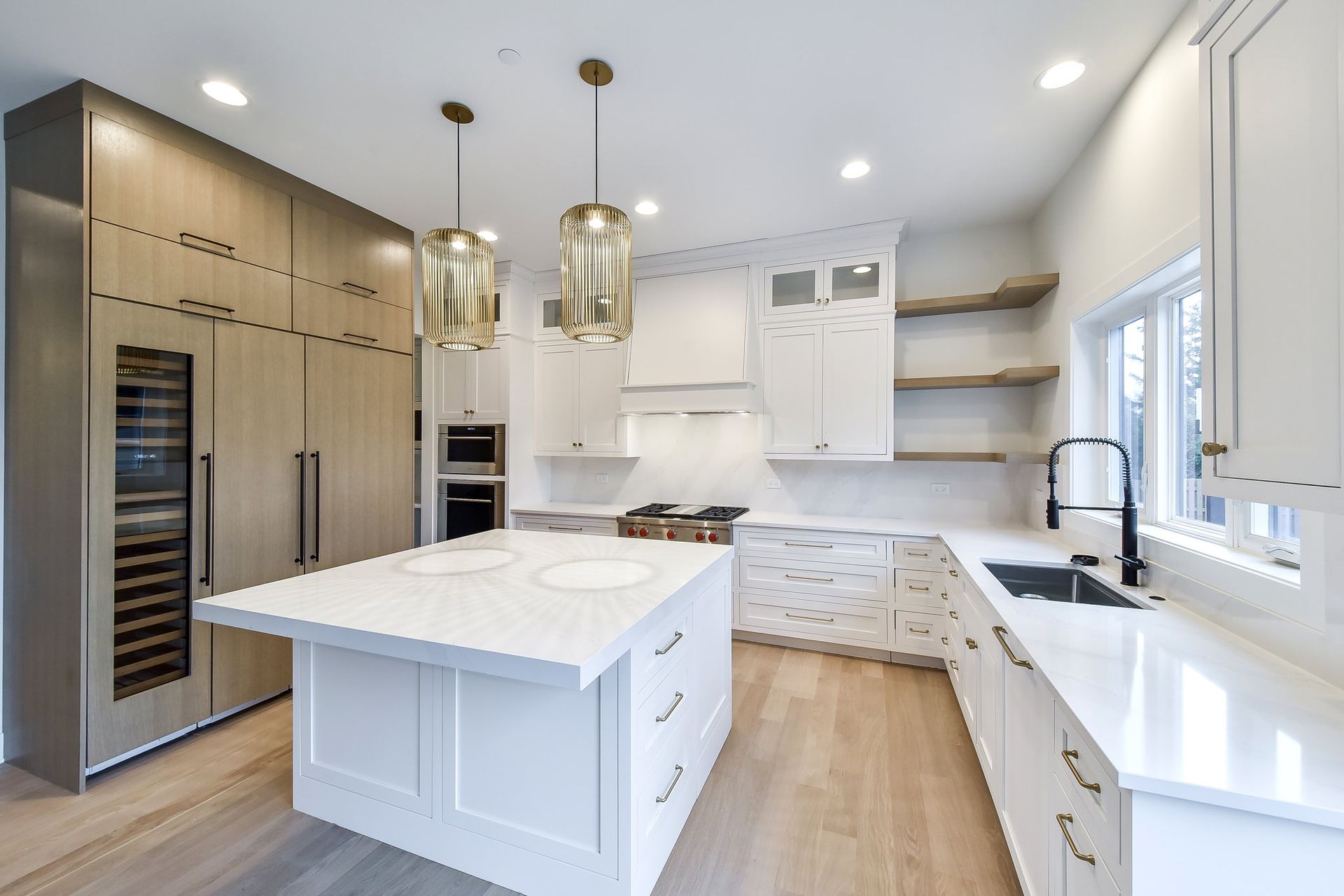 A kitchen with white cabinets , stainless steel appliances , and a large island.