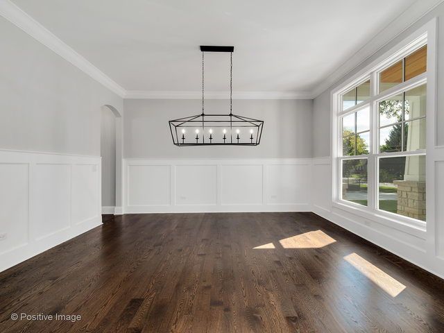 An empty dining room with hardwood floors and a chandelier