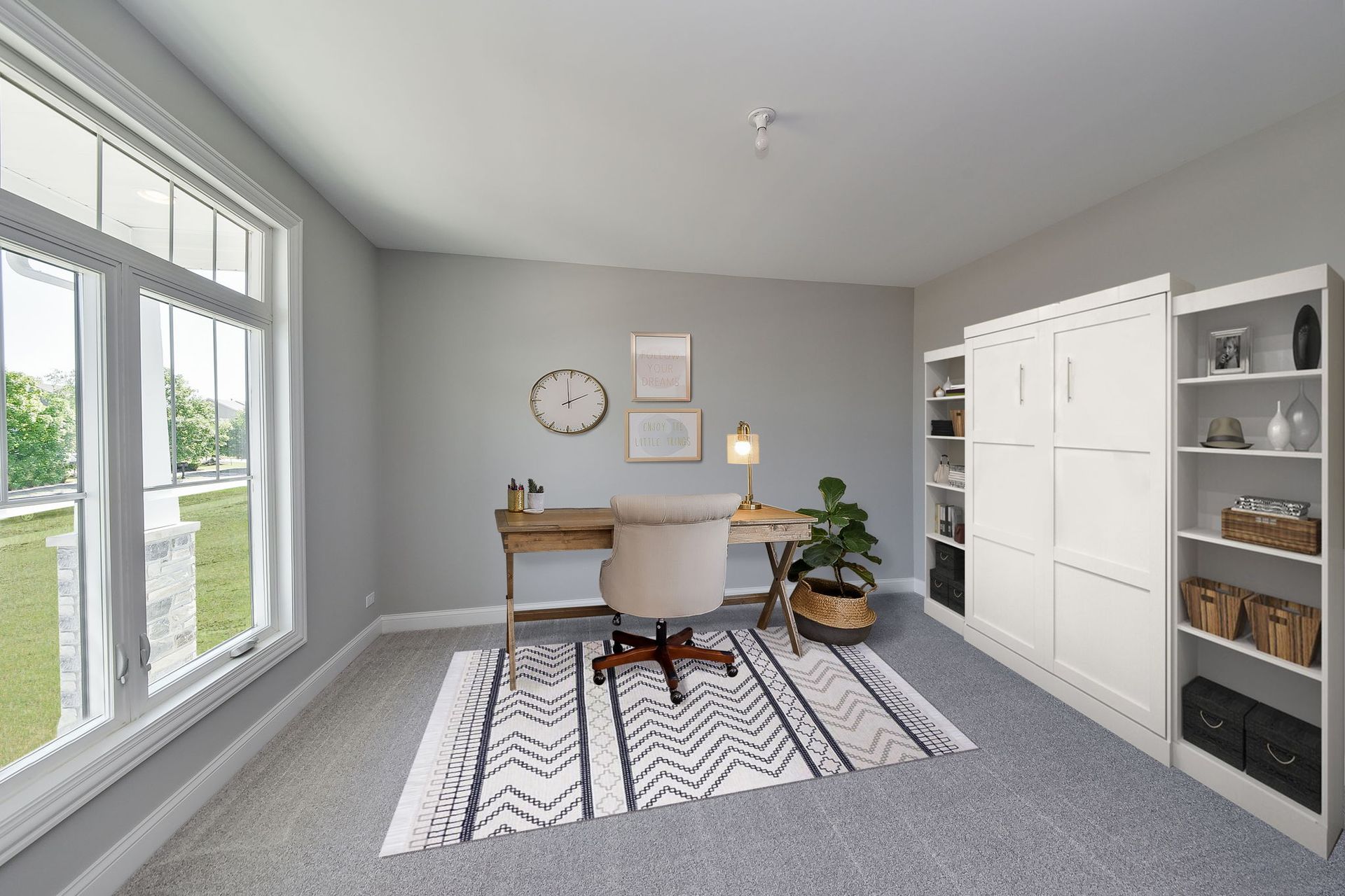 A room with a desk , chair , rug and a clock on the wall.