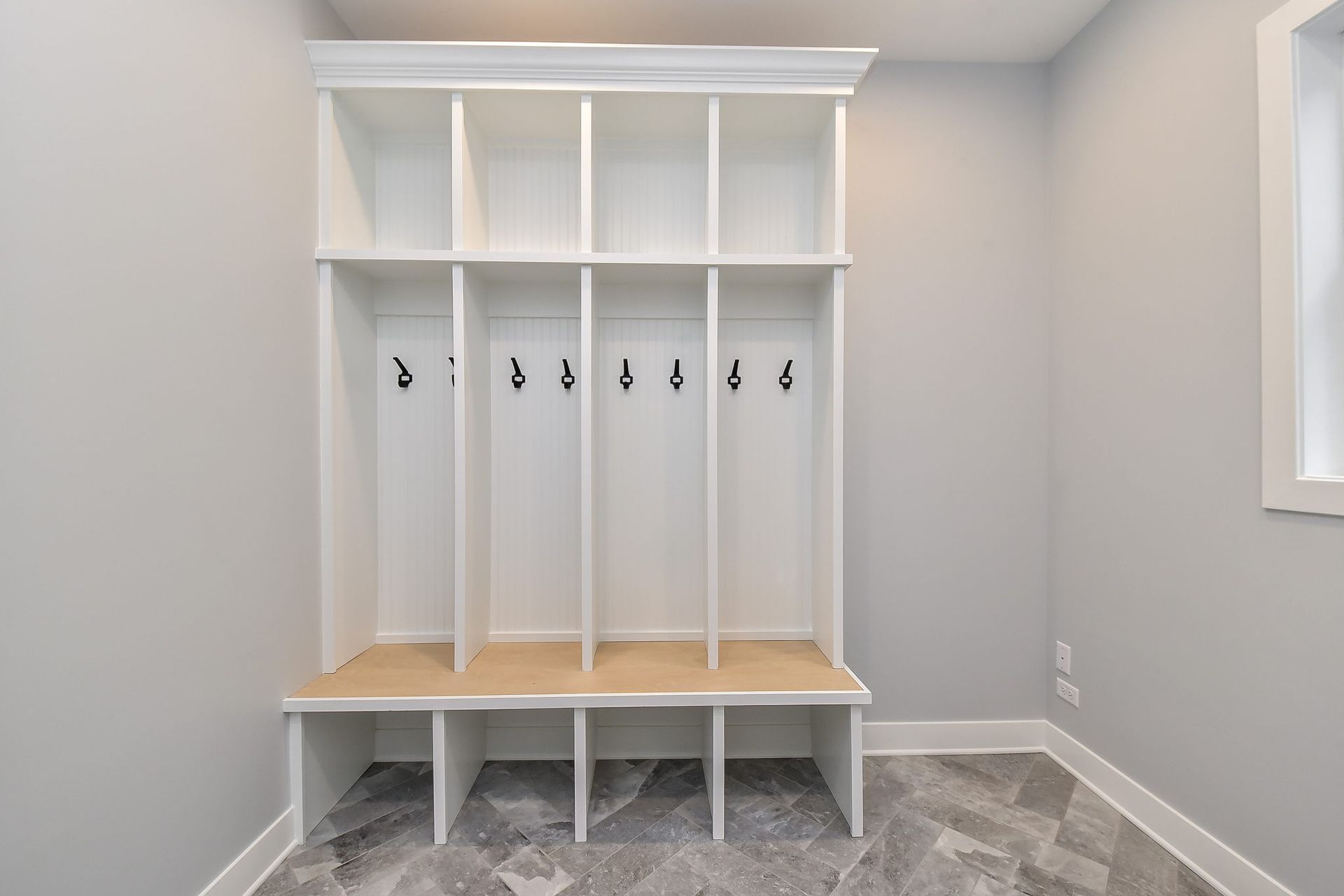 There is a bench in the middle of the room with hooks on the wall.