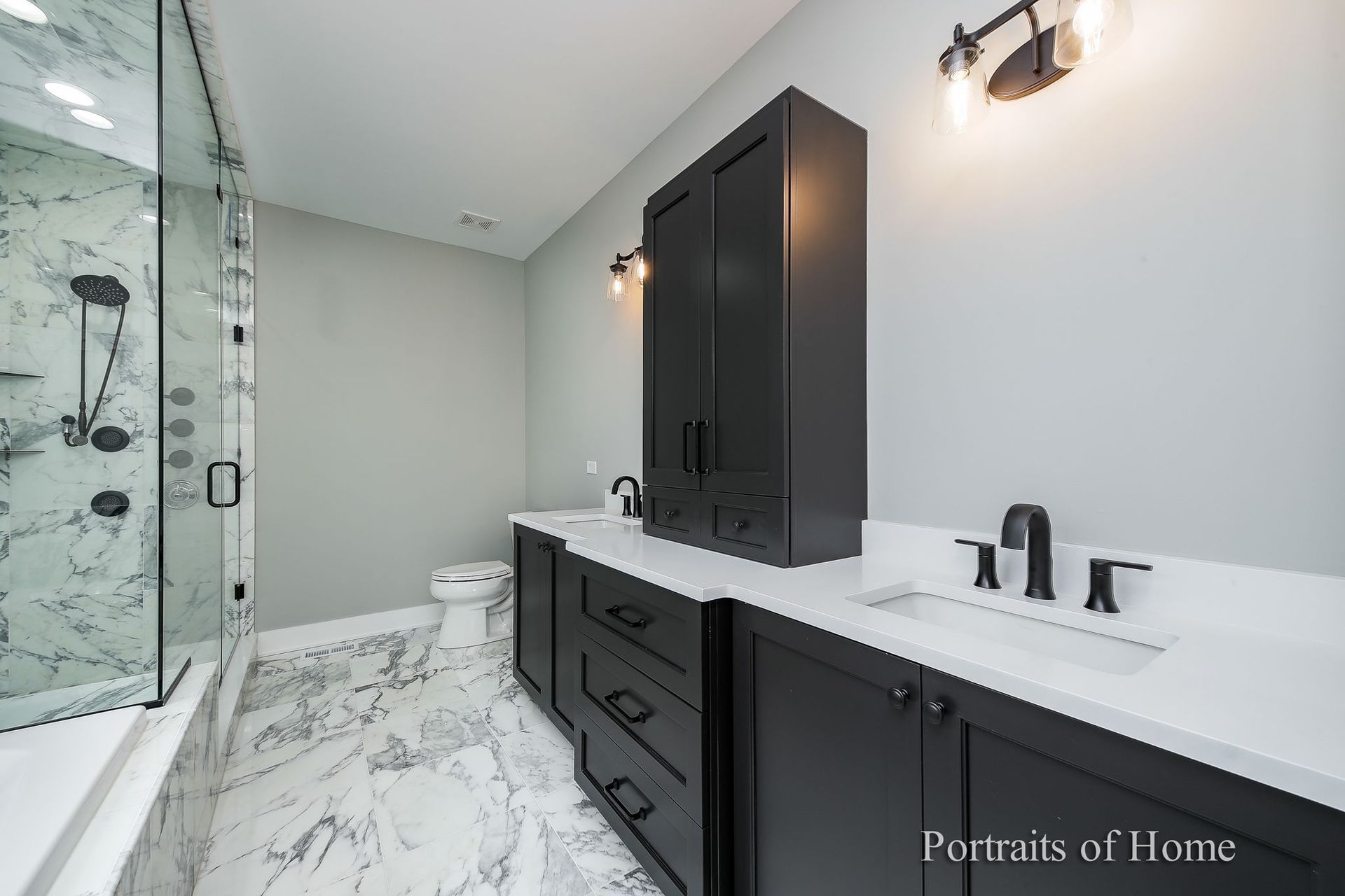 A bathroom with black cabinets , a toilet , a sink and a shower.
