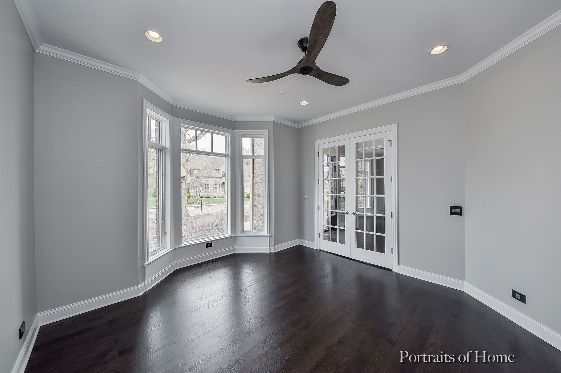 An empty room with a ceiling fan and a lot of windows.