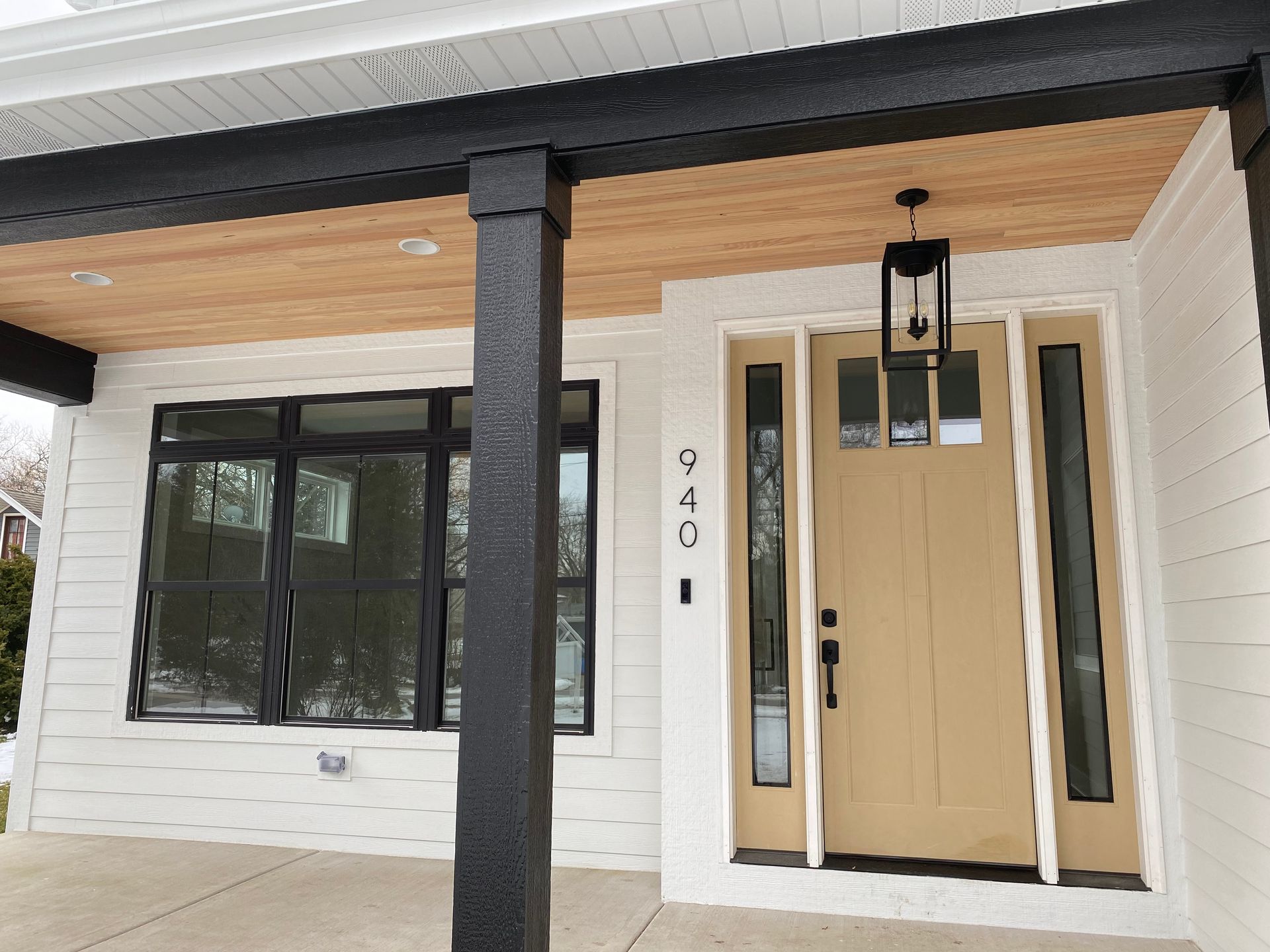 A white house with a brown door and a black porch