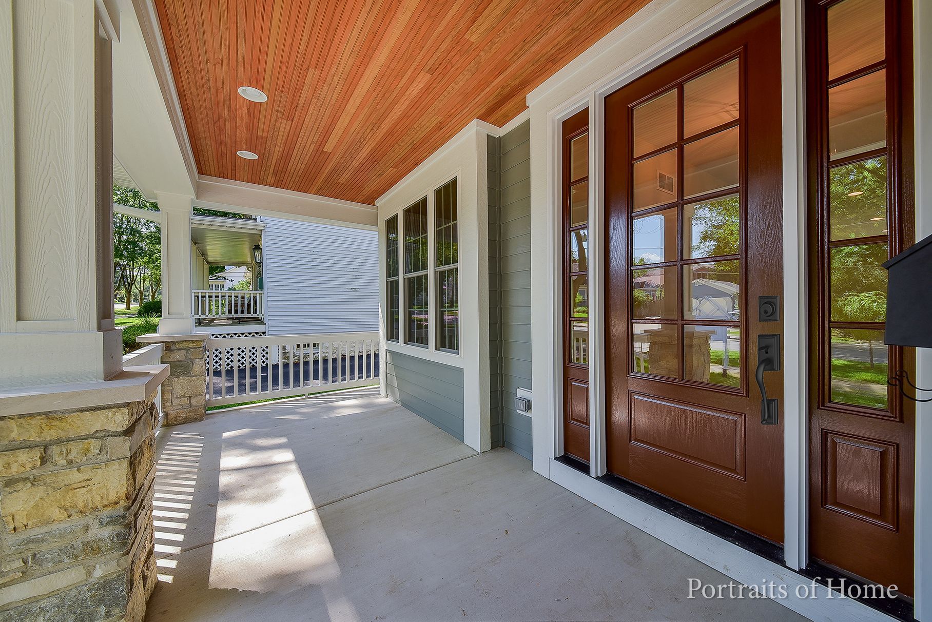 A porch with a wooden ceiling and brown doors