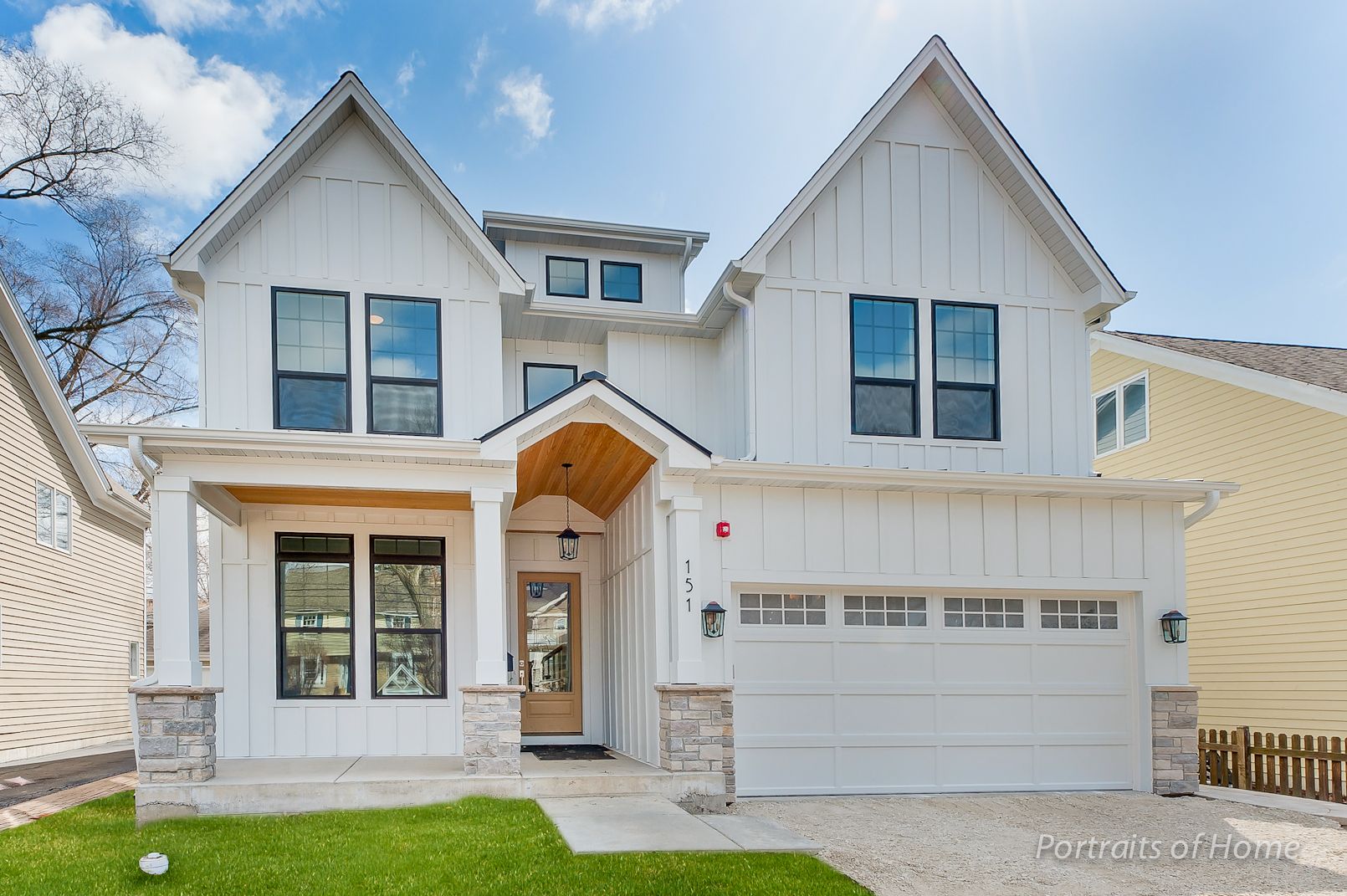 A large white house with a large garage and a fence in front of it.