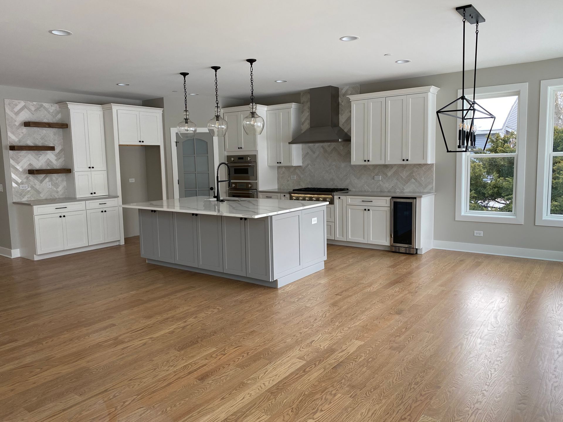 An empty kitchen with white cabinets and hardwood floors