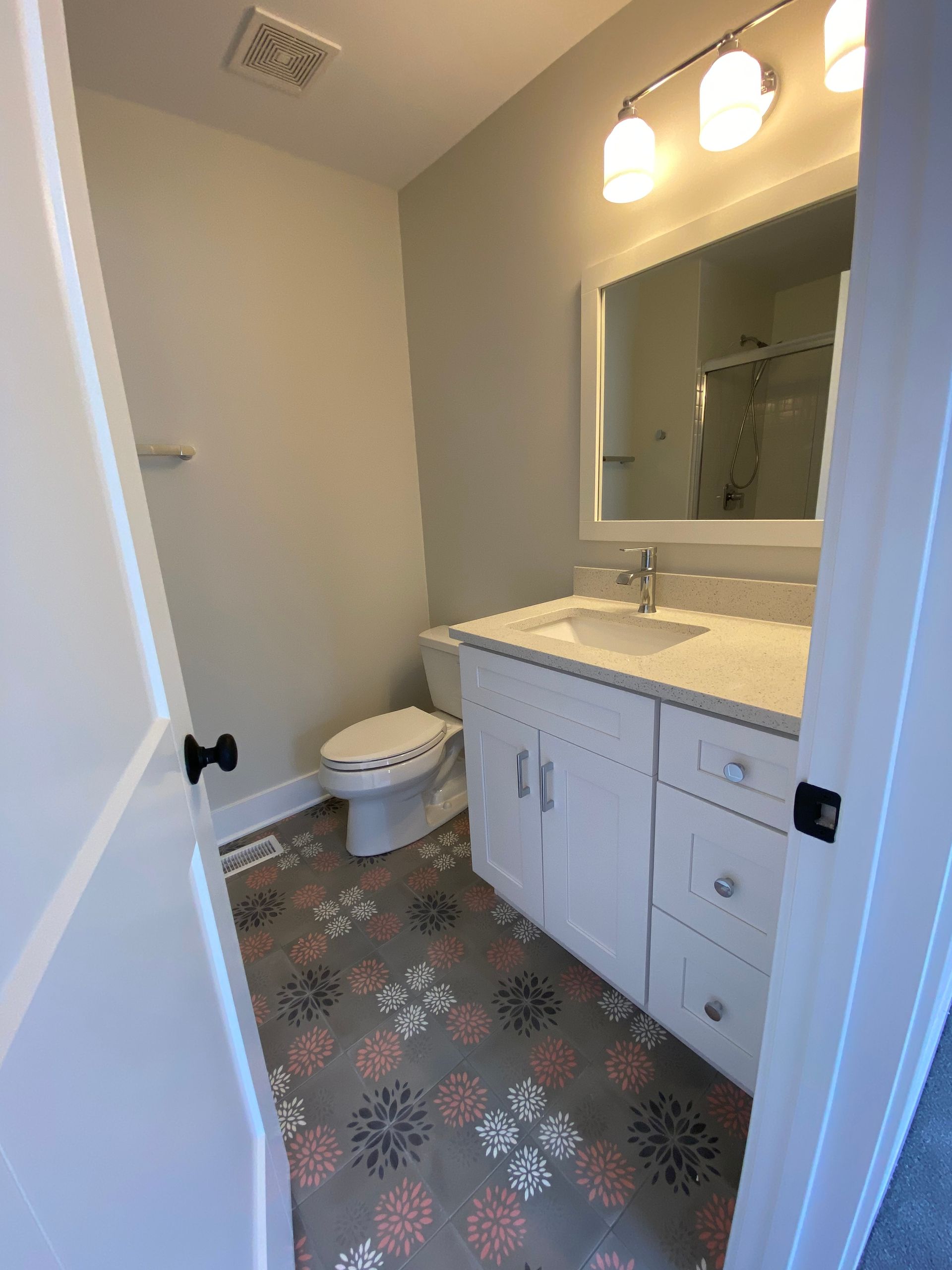 A bathroom with a toilet , sink and mirror.