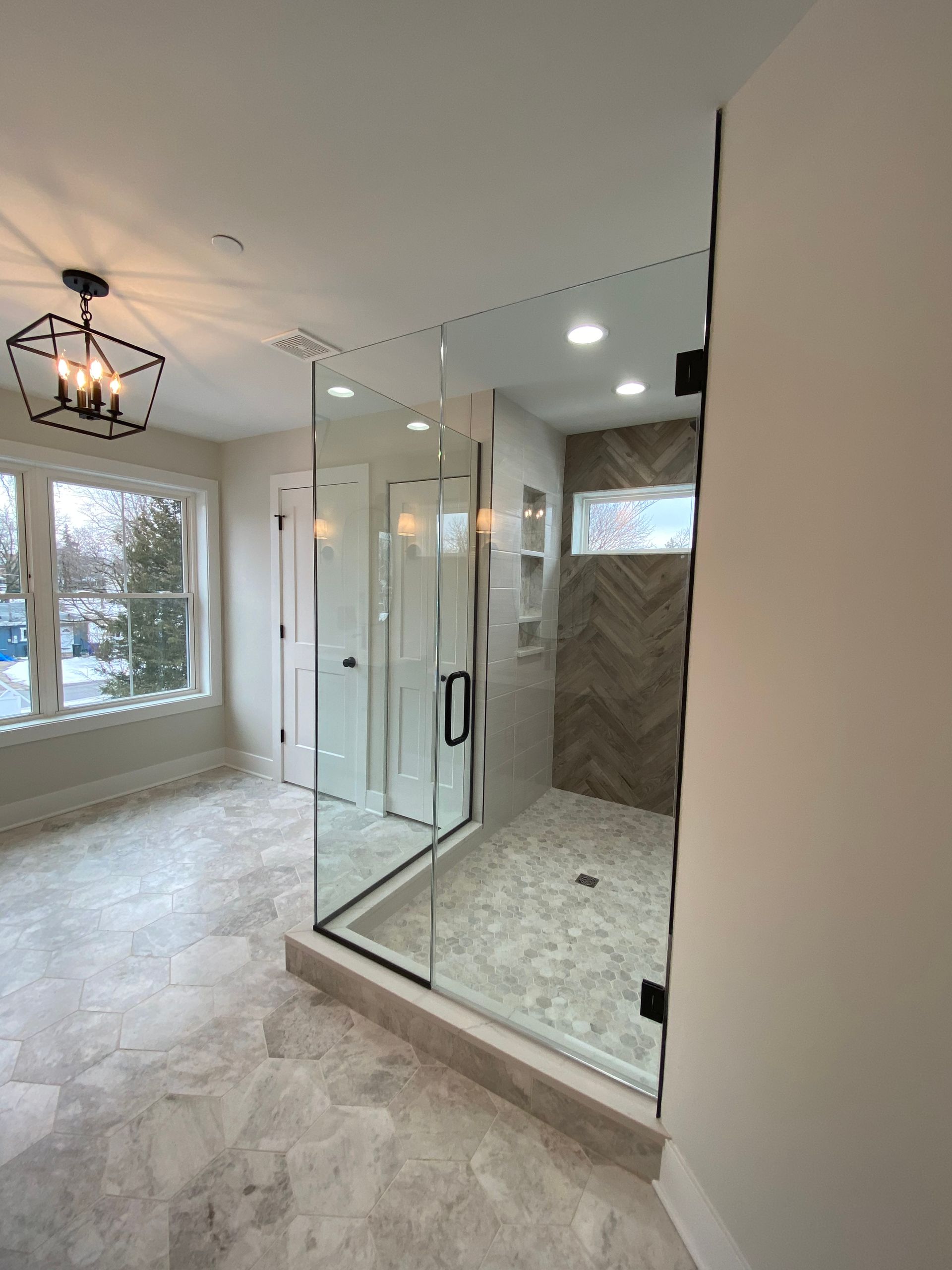 A bathroom with a walk in shower and a large window.
