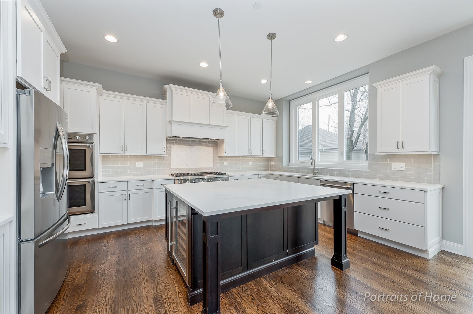 A kitchen with white cabinets , stainless steel appliances , and a large island.