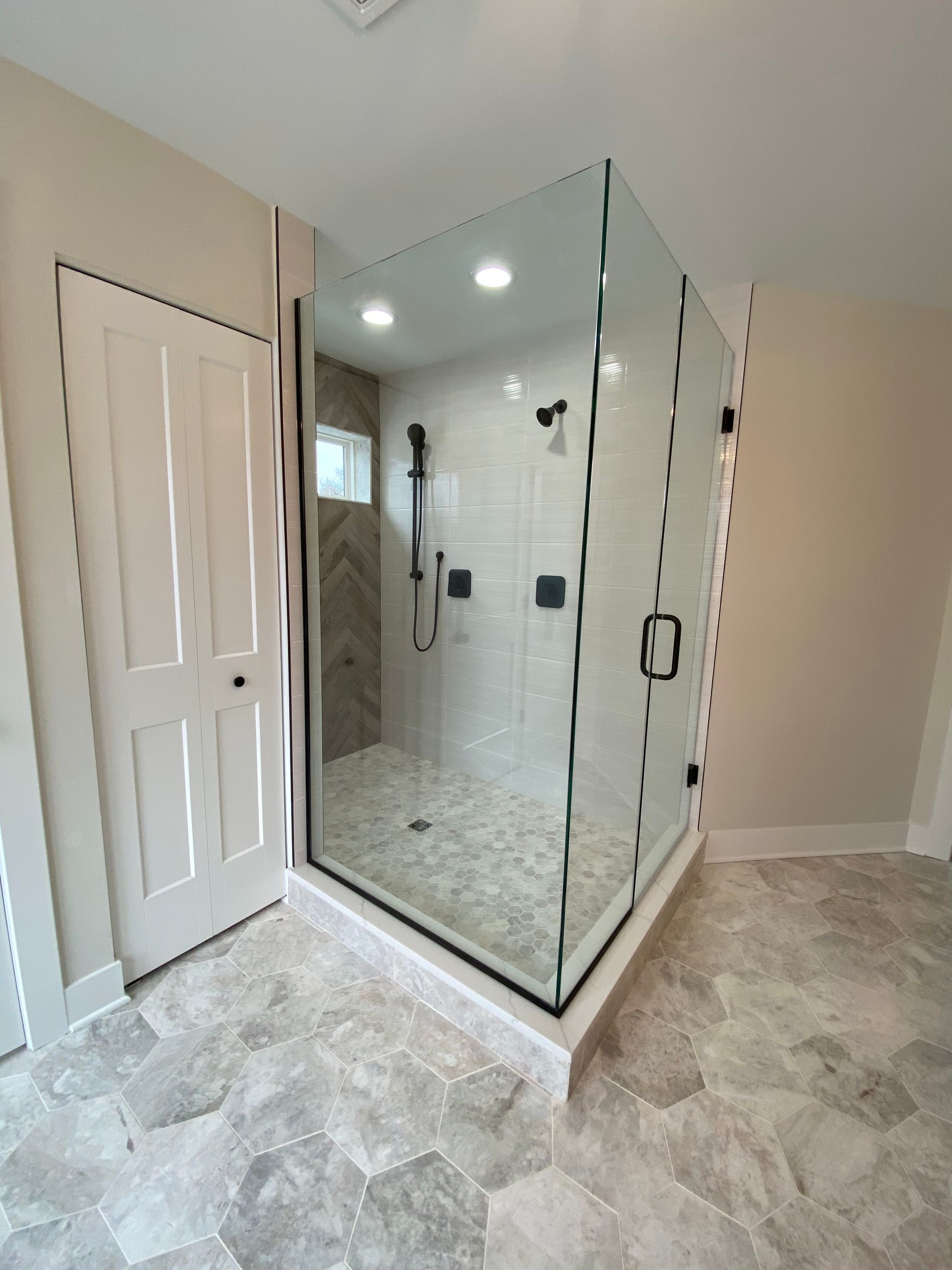 A bathroom with a walk in shower with a glass door.