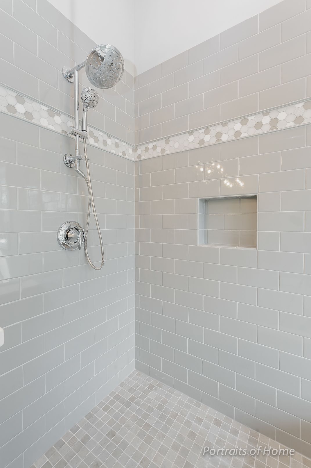 A walk in shower with a shower head and a niche in the wall.