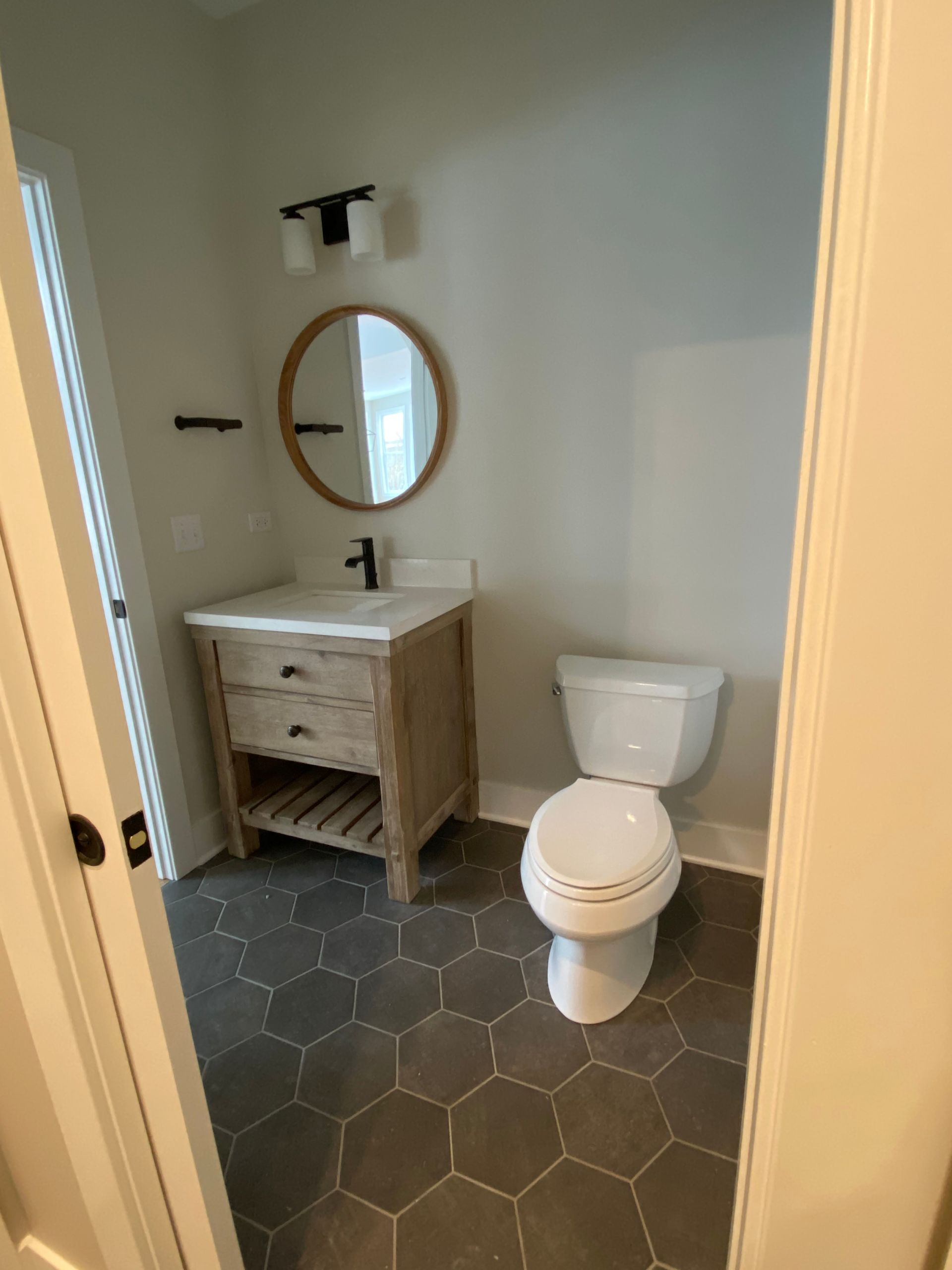 A bathroom with a toilet , sink and mirror.