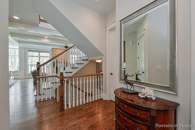 A hallway with a staircase and a mirror on the wall.