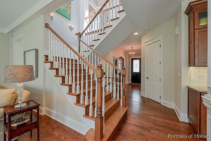 A wooden staircase with white railings is leading up to the second floor of a house.