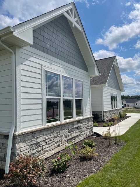 A white house with a gray roof and a lot of windows.