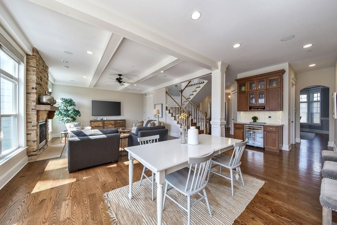 A living room and dining room in a house with hardwood floors and a white table and chairs.