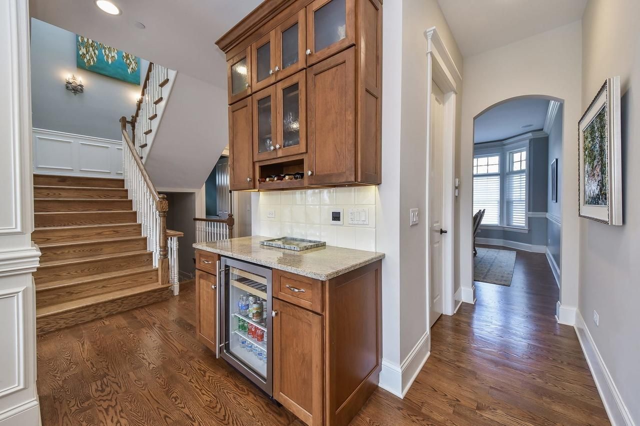 A kitchen with wooden cabinets , granite counter tops , a refrigerator and stairs.
