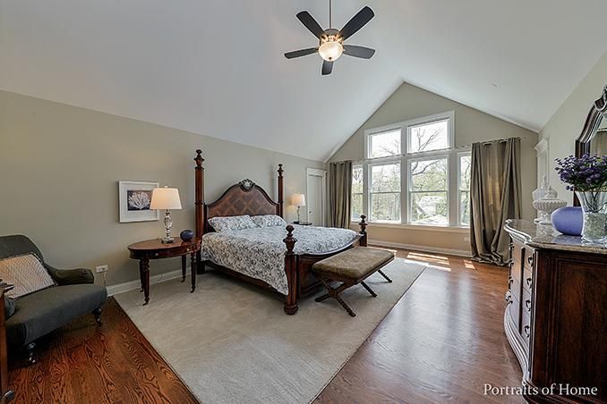 A bedroom with a large bed and a ceiling fan