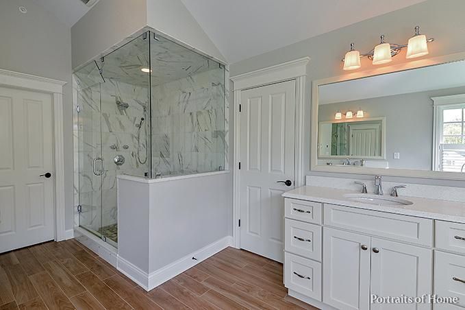 A bathroom with a walk in shower , sink and mirror.