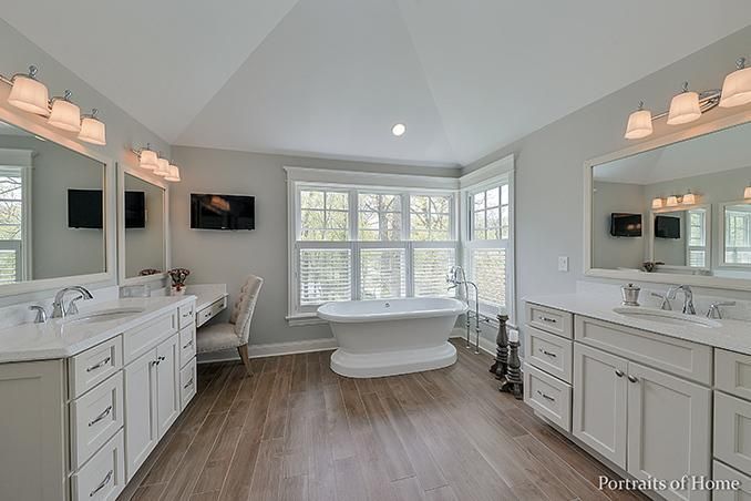 A bathroom with two sinks , a tub , and two mirrors.