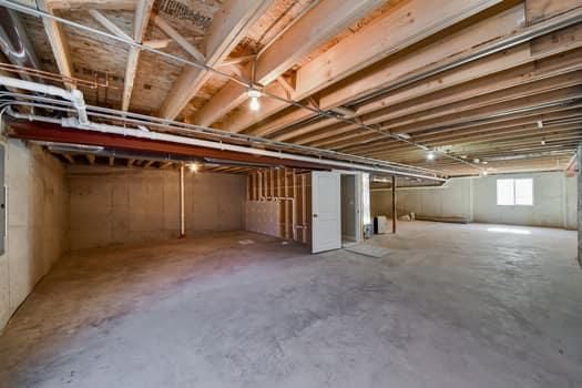 An empty basement with a wooden ceiling and concrete floor.