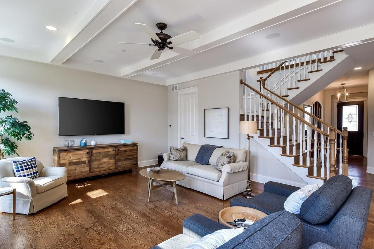 A living room with a couch , chairs , and a flat screen tv.