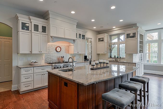 A kitchen with white cabinets , granite counter tops , and a large island.