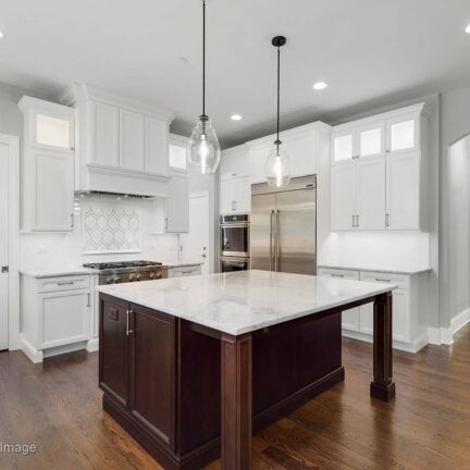 A kitchen with white cabinets and a large island in the middle.