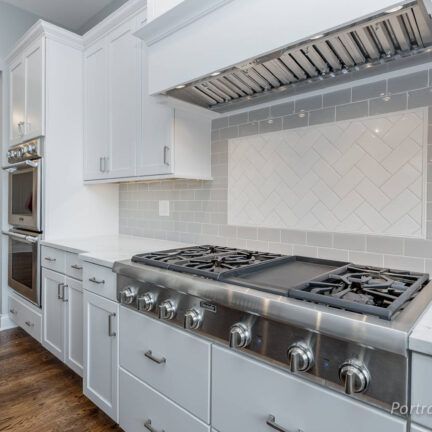 A kitchen with white cabinets and a stove top oven
