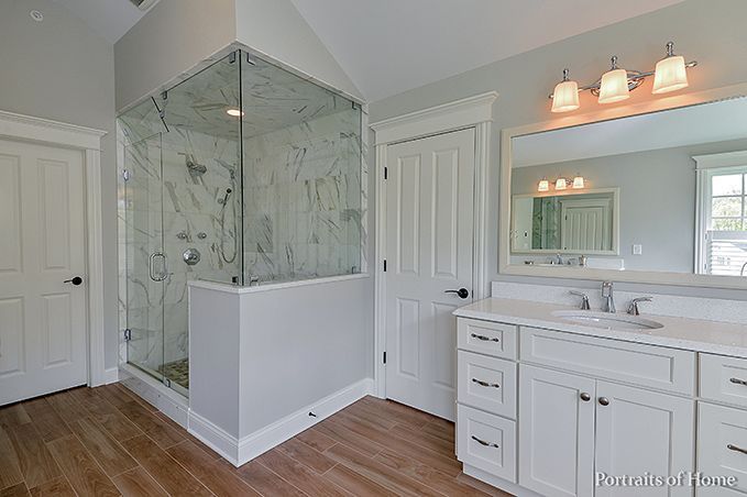 A bathroom with a walk in shower , sink and mirror.