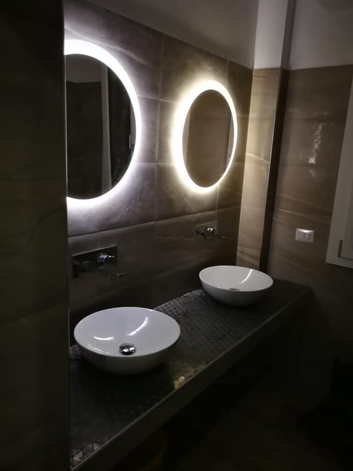 Un bagno con due lavandini e uno specchio rotondo