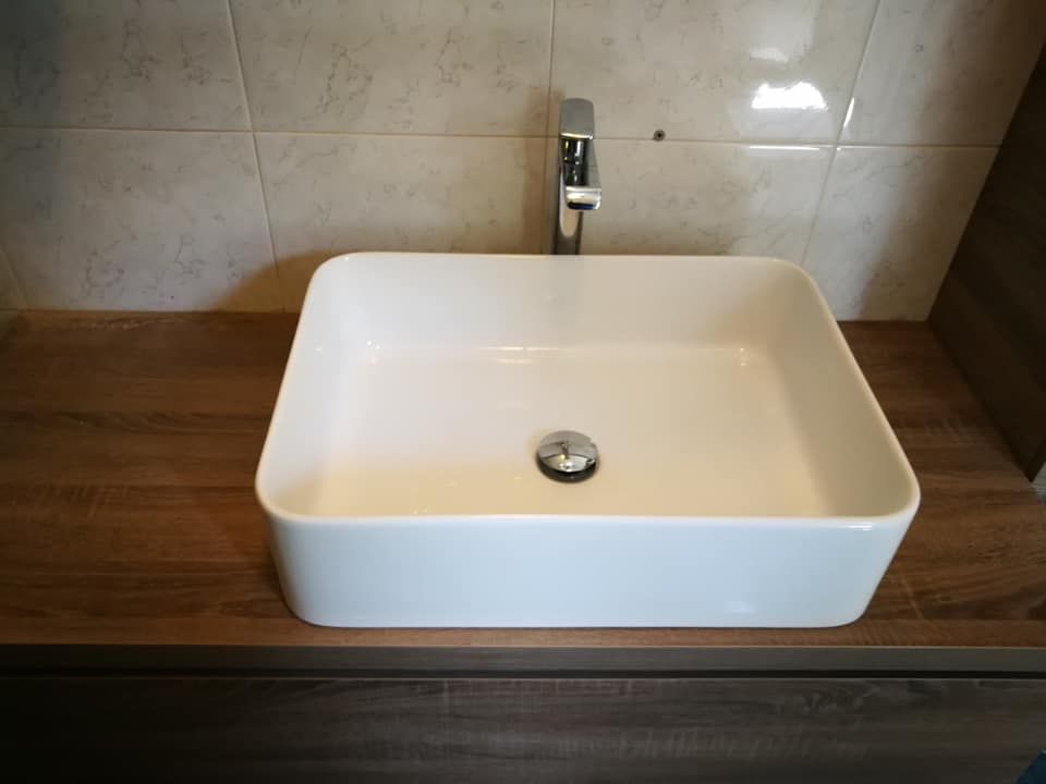 Un lavandino del bagno è appoggiato su un ripiano in legno