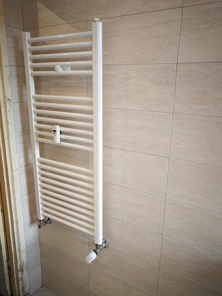 Un portasciugamani bianco è appeso a una parete piastrellata in un bagno.