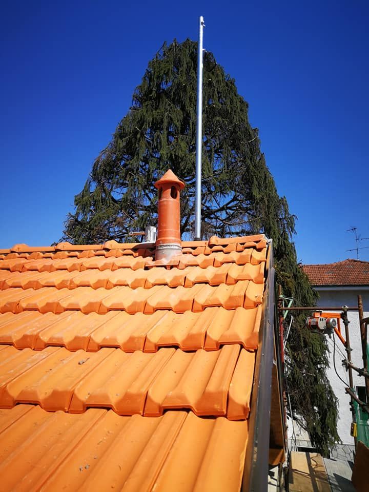 Un tetto con un camino e un albero sullo sfondo