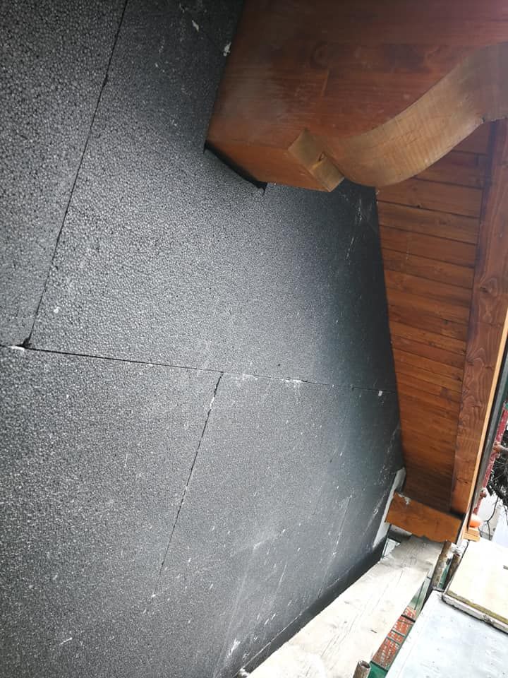 Un muro nero con un tetto in legno sullo sfondo.