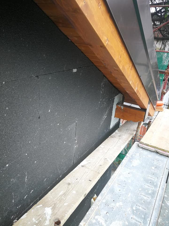 Una trave di legno è appoggiata su un'impalcatura accanto a un muro.