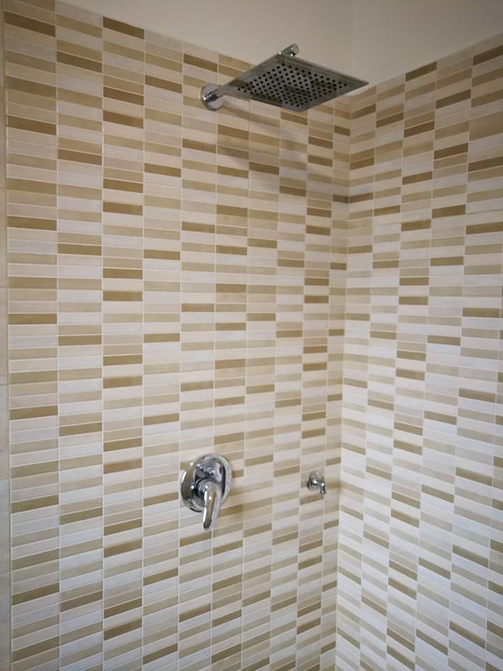 Una doccia con parete piastrellata e soffione