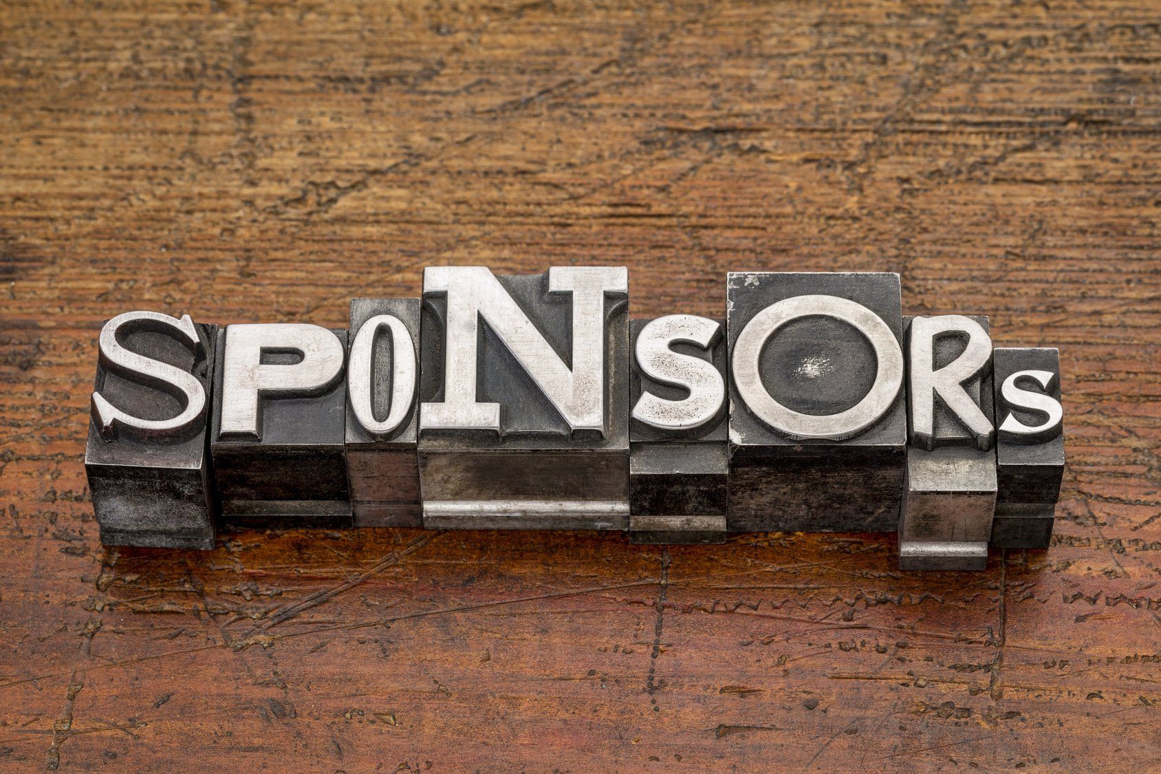 The word sponsors is written in vintage letterpress type on a wooden table.